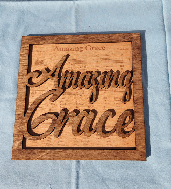 Wooden plaque with 'Amazing Grace' engraving on a light blue background