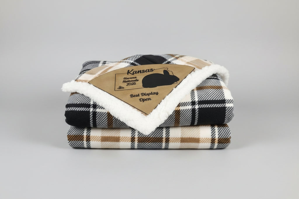 Brown leather patch with 'Kansas Havana Nationals 2025 Best Display Open' text on a plaid blanket.