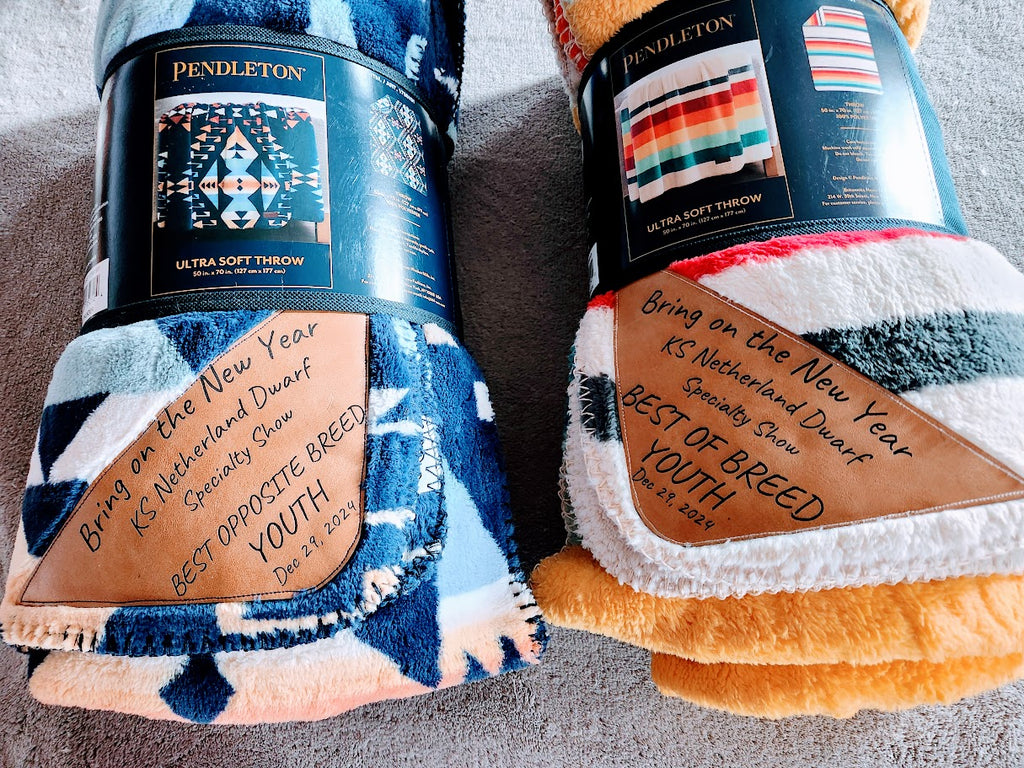 Two Pendleton blankets with branded labels on a gray surface
