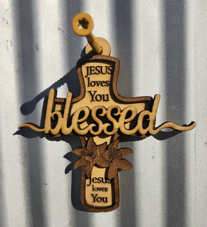 Decorative cross with 'Jesus loves You' and 'blessed' text on a metal surface