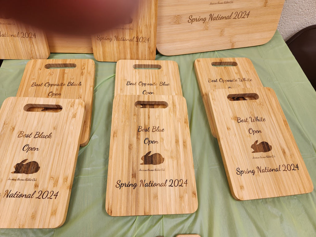 Set of wooden cutting boards with engraved text and graphics on a green surface