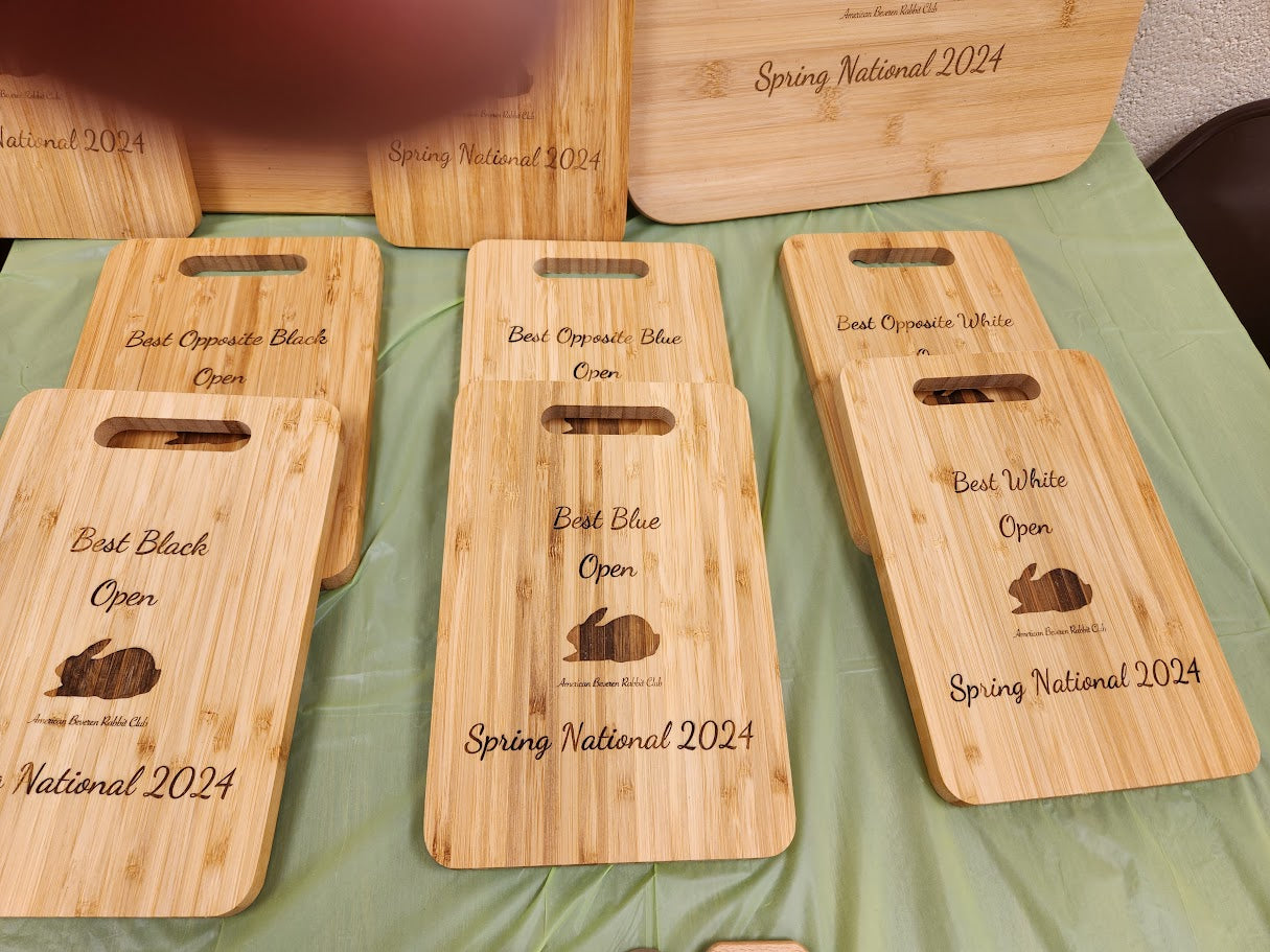 Set of wooden cutting boards with engraved text and graphics on a green surface