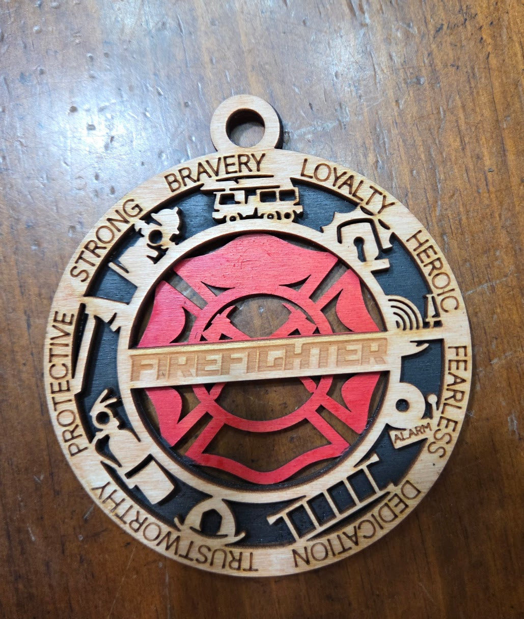 Decorative pendant with firefighter design and engraved text on a wooden surface