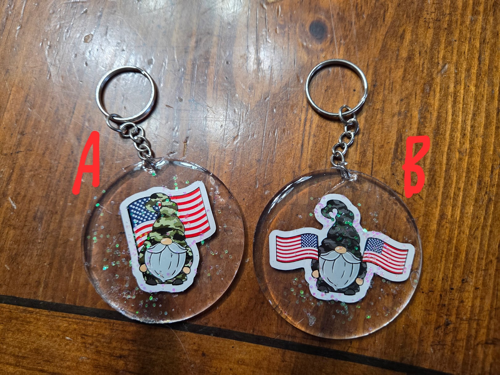 Two keychains with a gnomes and American flag design on a wooden surface.