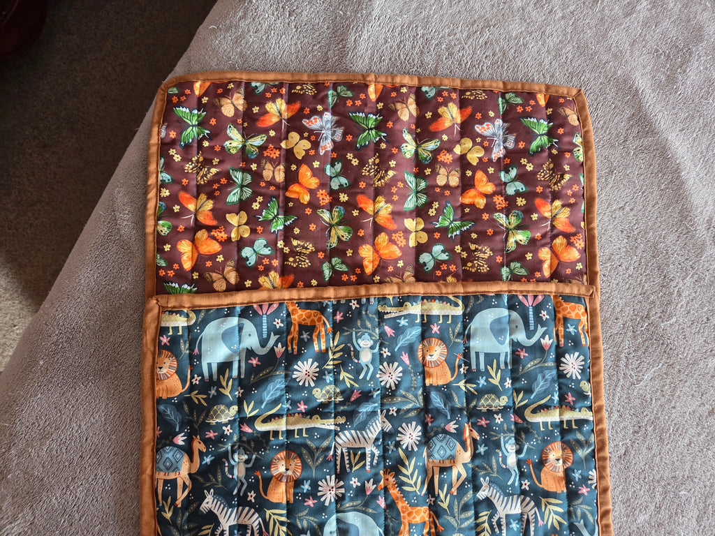 Two fabric grooming mats with animal and nature patterns on a textured surface.