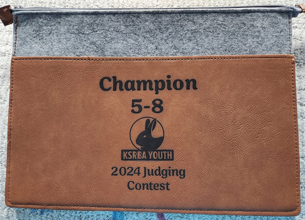 Brown leather pouch with 'Champion 5-8' and 'KSKRA Youth 2024 Judging Contest' text on a gray background