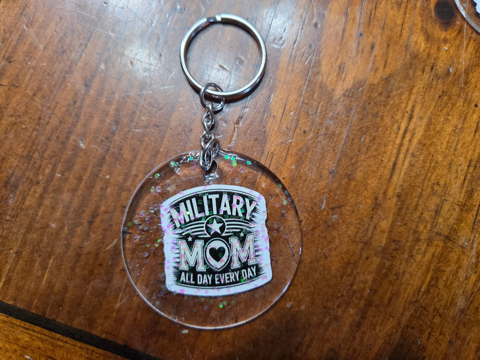 Keychain with 'Military Mom All Day Every Day' text on a wooden surface