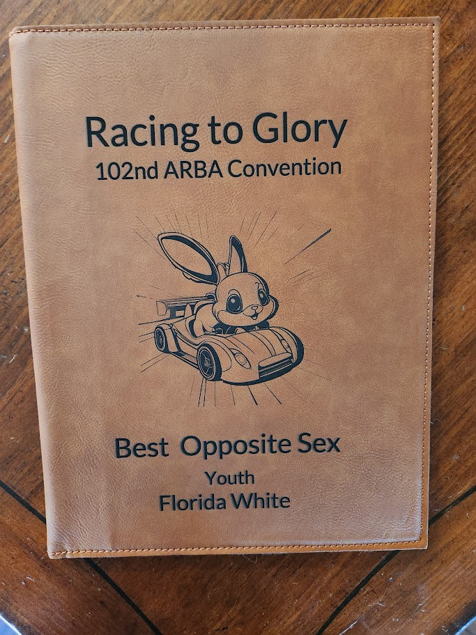 Brown leather notebook with text and a rabbit illustration on a wooden surface