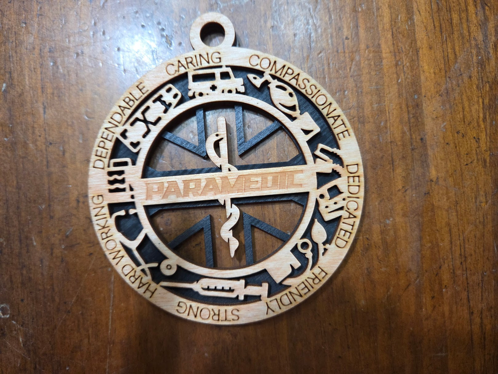 Wooden pendant with 'Paramedic' text and symbols on a wooden surface