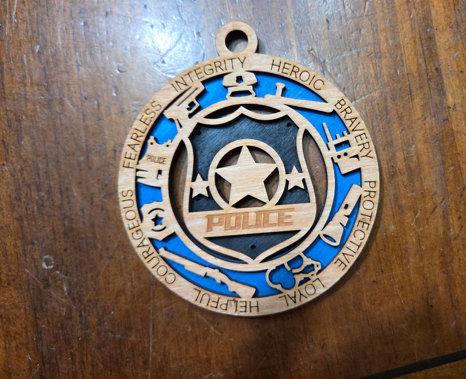 Wooden police badge ornament with blue and gold colors on a wooden surface