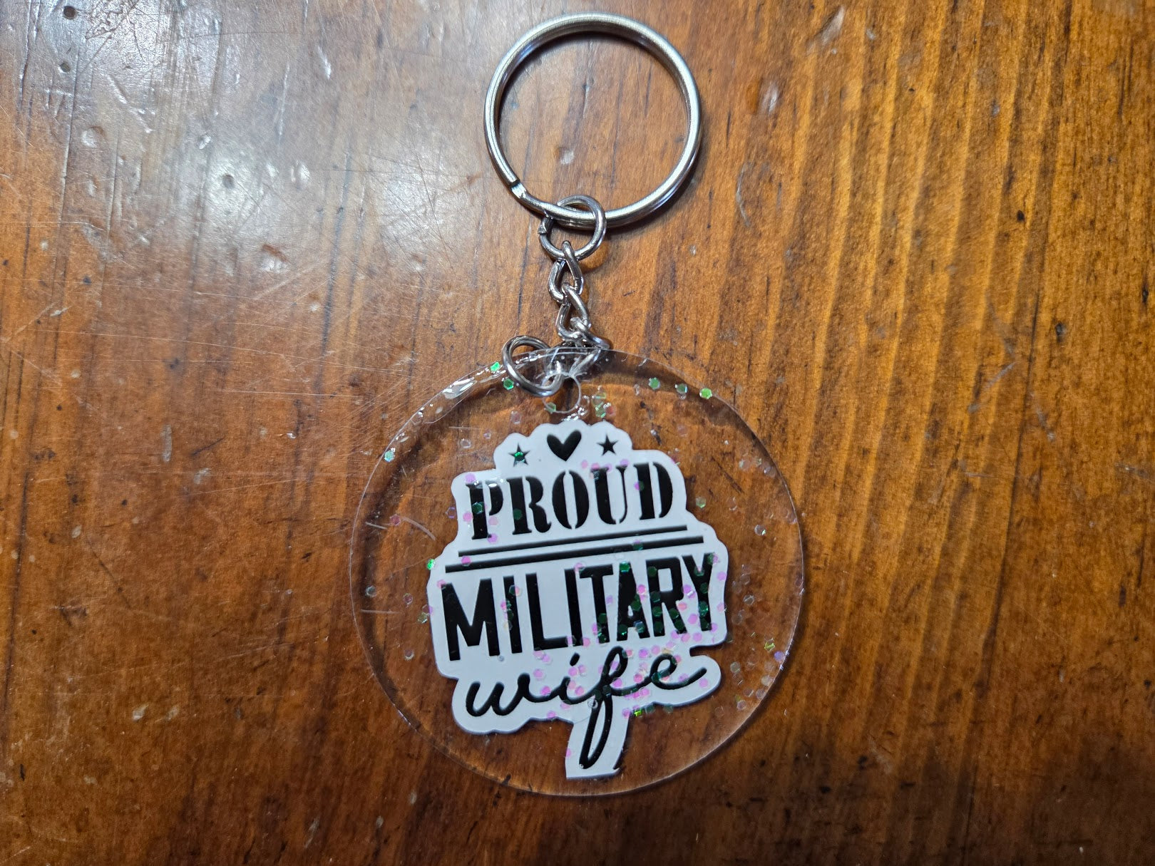 Keychain with 'Proud Military Wife' text on a wooden surface