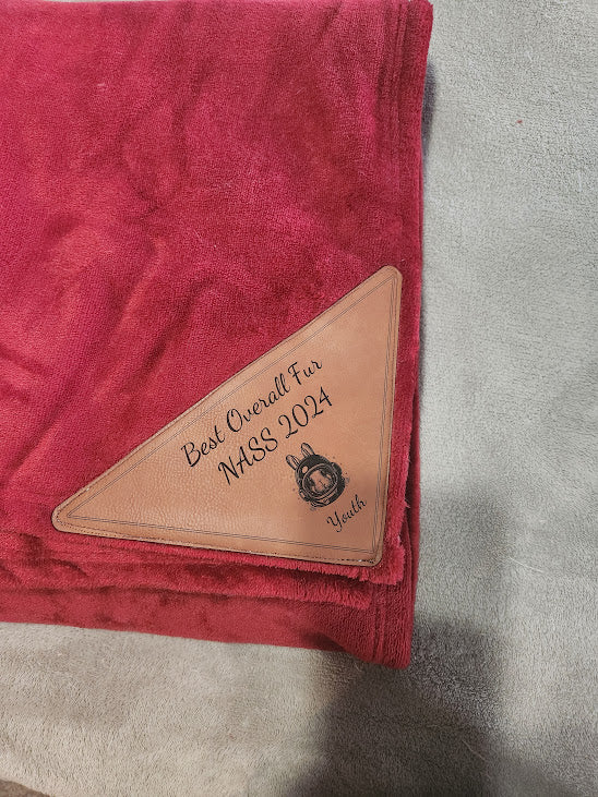 Red fabric with a leather patch displaying 'Best Overall Fur NASS 2024' on a gray background