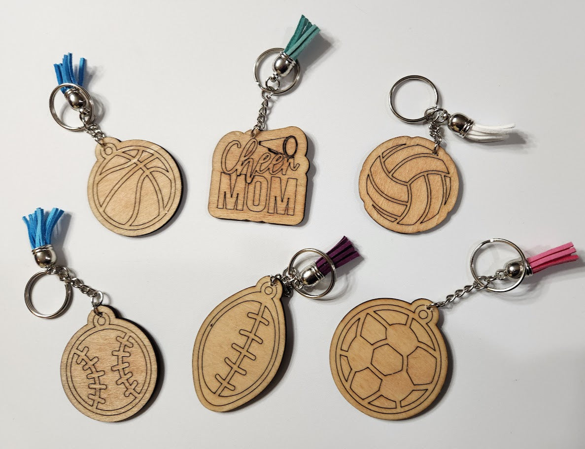 Set of wooden keychains with sports-themed designs on a white background