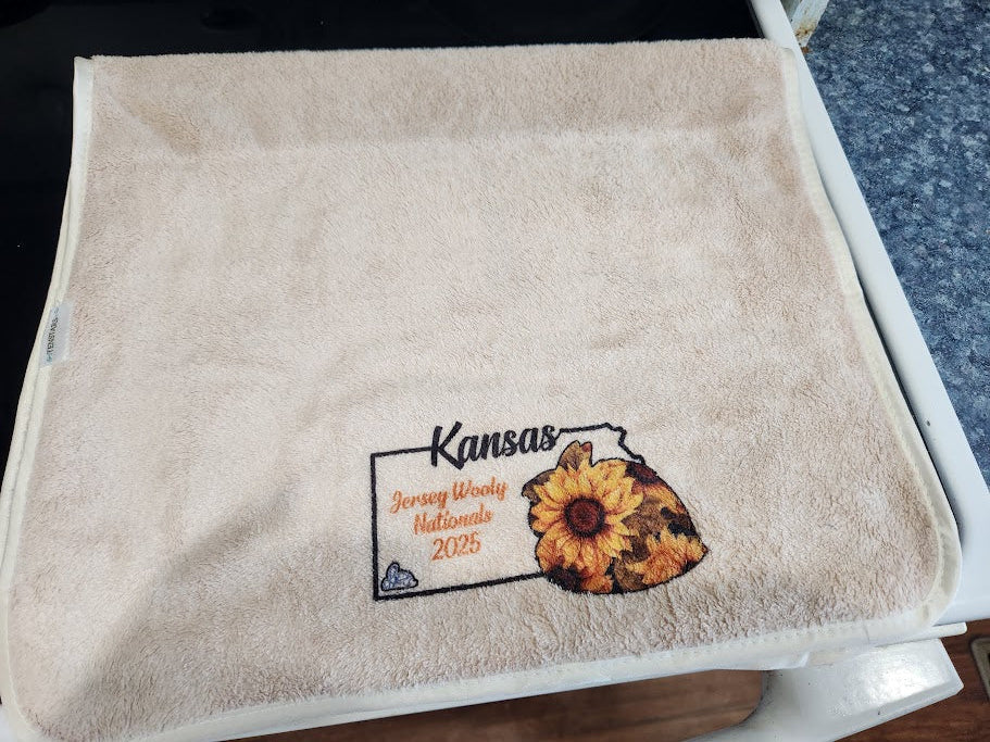 Beige towel with printed design of Kansas featuring a sunflower rabbit.