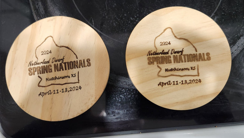 Two wooden coasters with engraved text on a dark surface